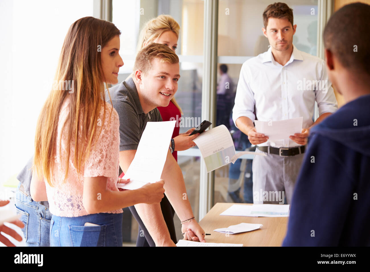 Teacher With College Students Standing By Desks In Classroom Stock