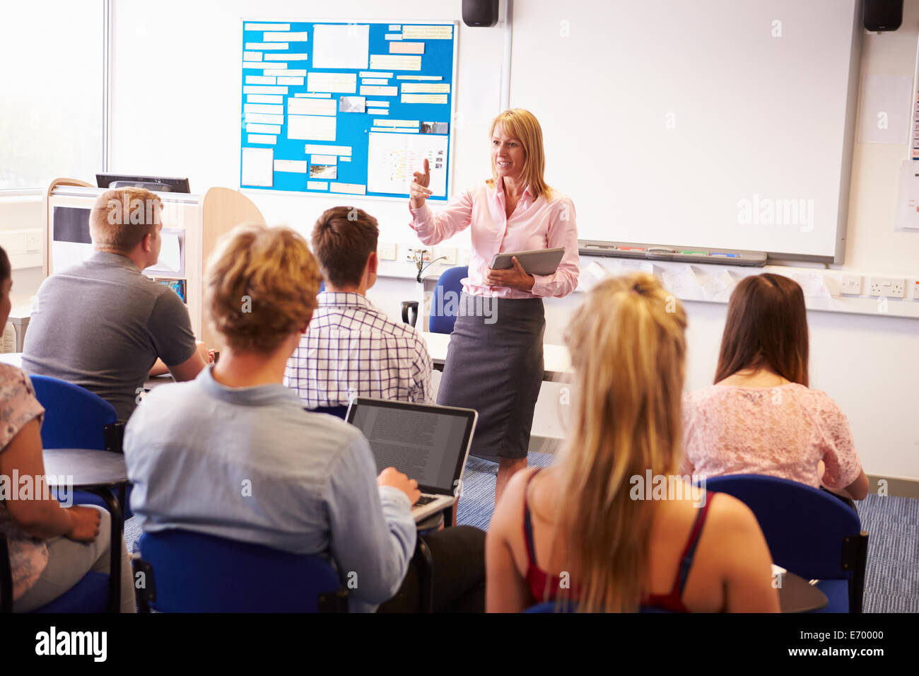 Teacher With College Students Giving Lesson In Classroom Stock Photo