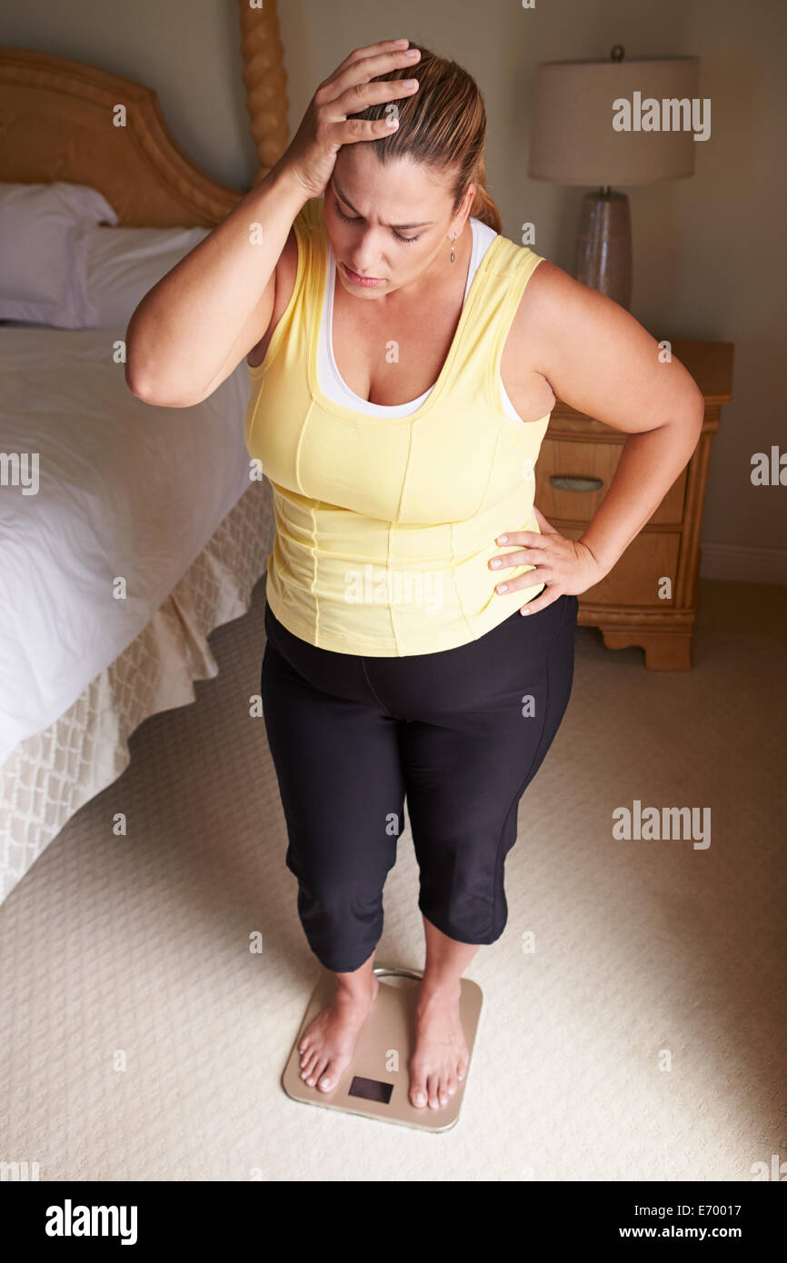 https://c8.alamy.com/comp/E70017/overweight-woman-weighing-herself-on-scales-in-bedroom-E70017.jpg