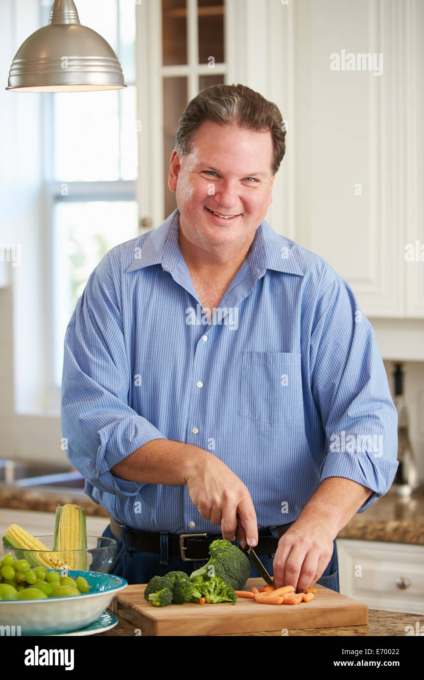 Overweight Man Preparing Vegetables in Kitchen Stock Photo