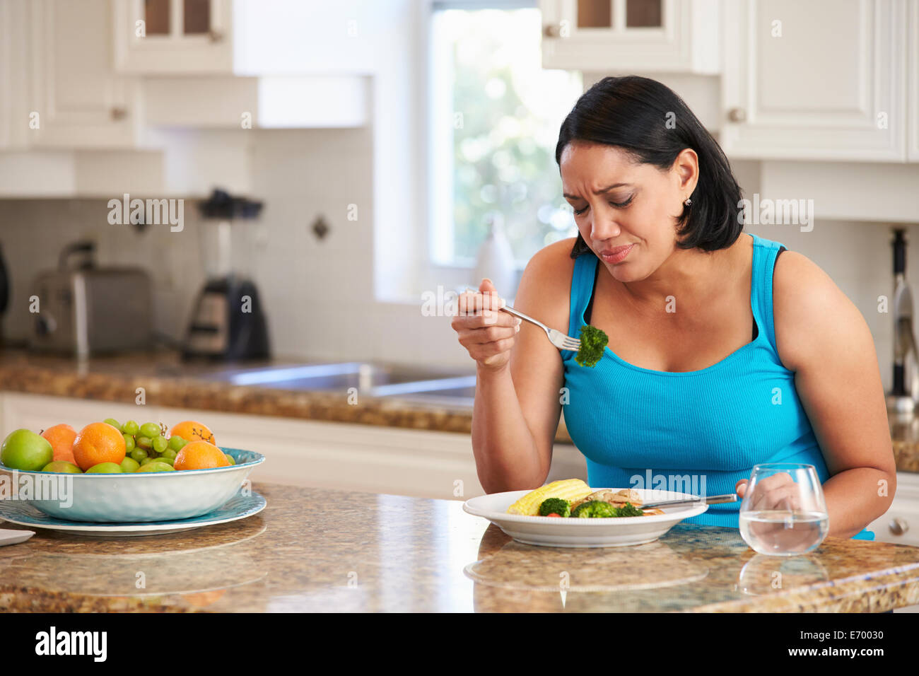 Fed Up Overweight Woman Eating Healthy Meal in Kitchen Stock Photo