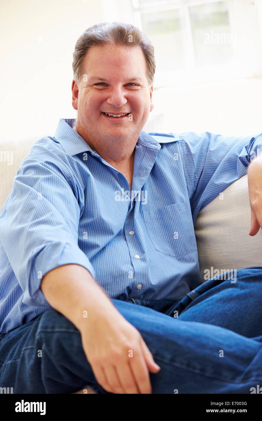 Portrait Of Overweight Man Sitting On Sofa Stock Photo