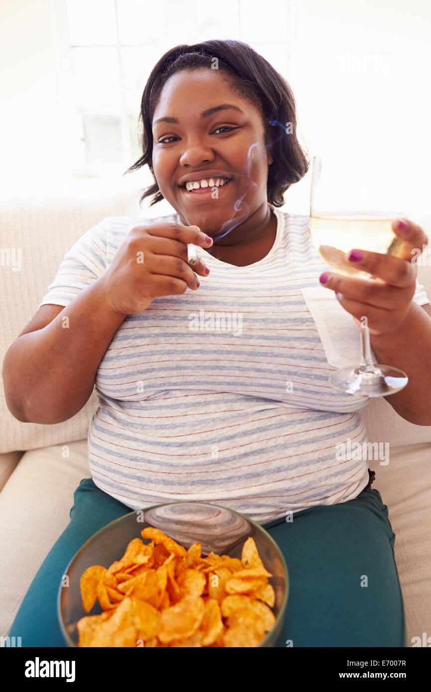Overweight Woman At Home Eating Chips And Drinking Wine Stock Photo Alamy