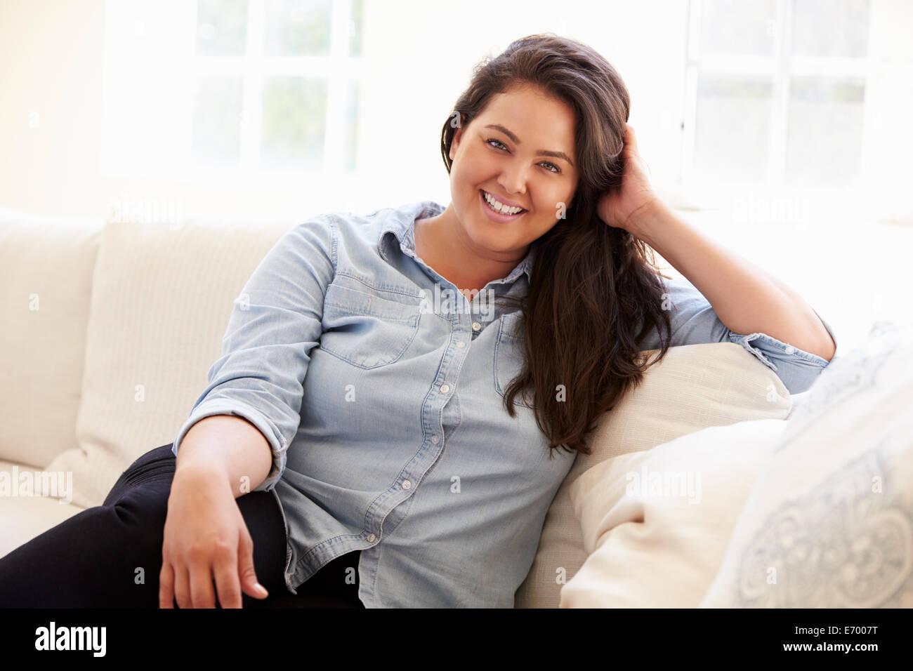 Portrait Of Overweight Woman Sitting On Sofa Stock Photo
