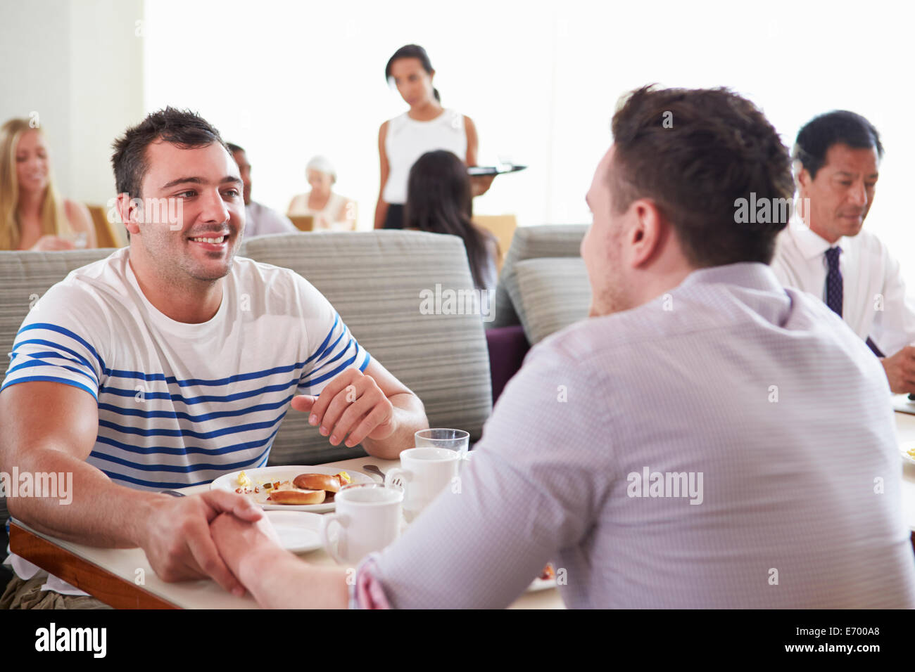 Male Couple Enjoying Breakfast In Hotel Restaurant Stock Photo