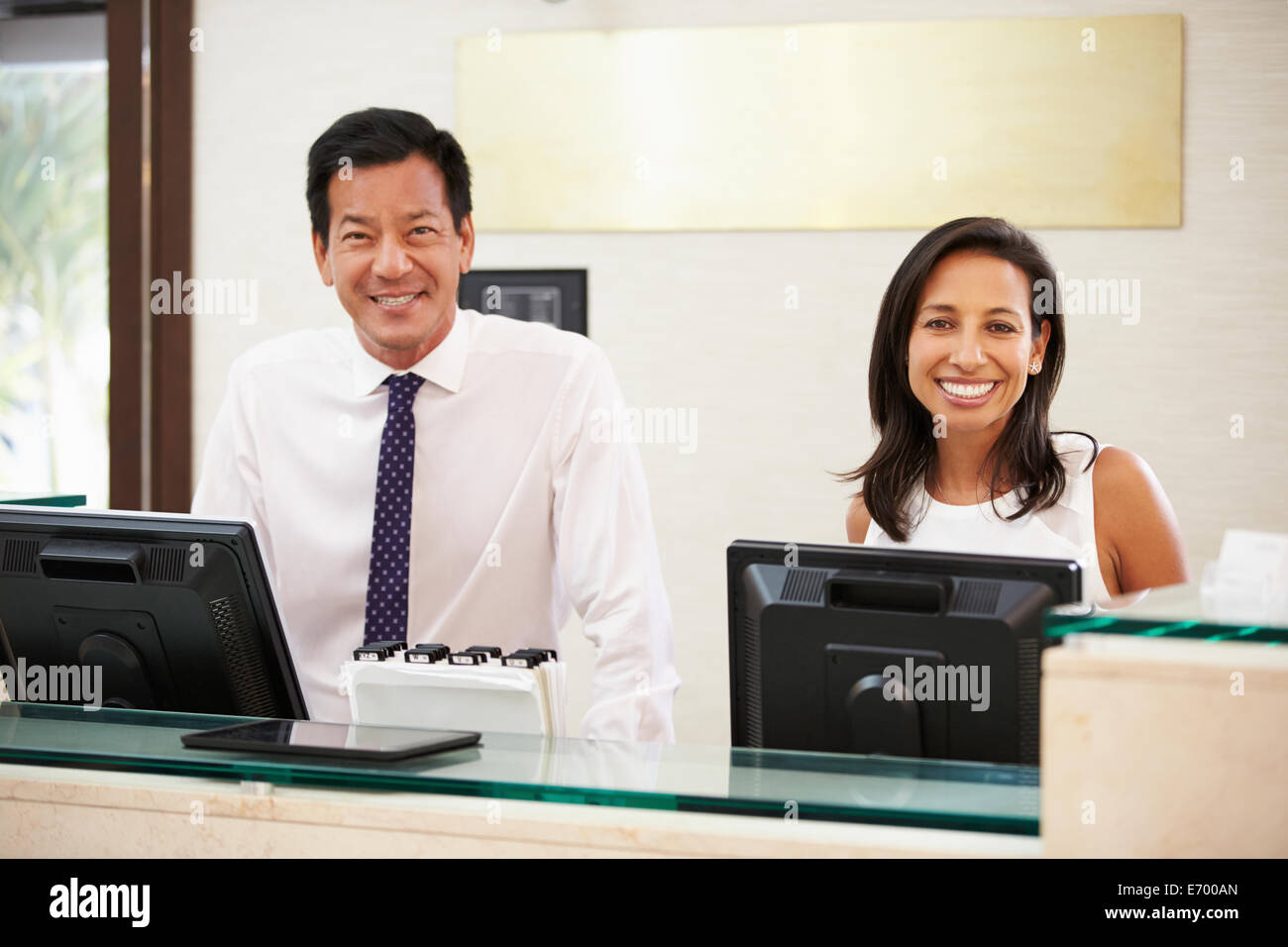 Portrait Of Reception Staff At Hotel Front Desk Stock Photo