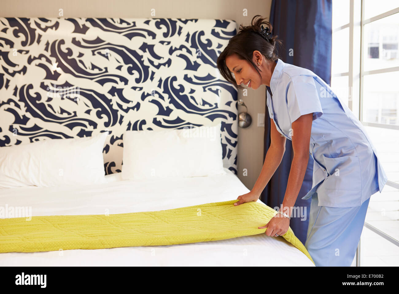 Maid Tidying Hotel Room And Making Bed Stock Photo