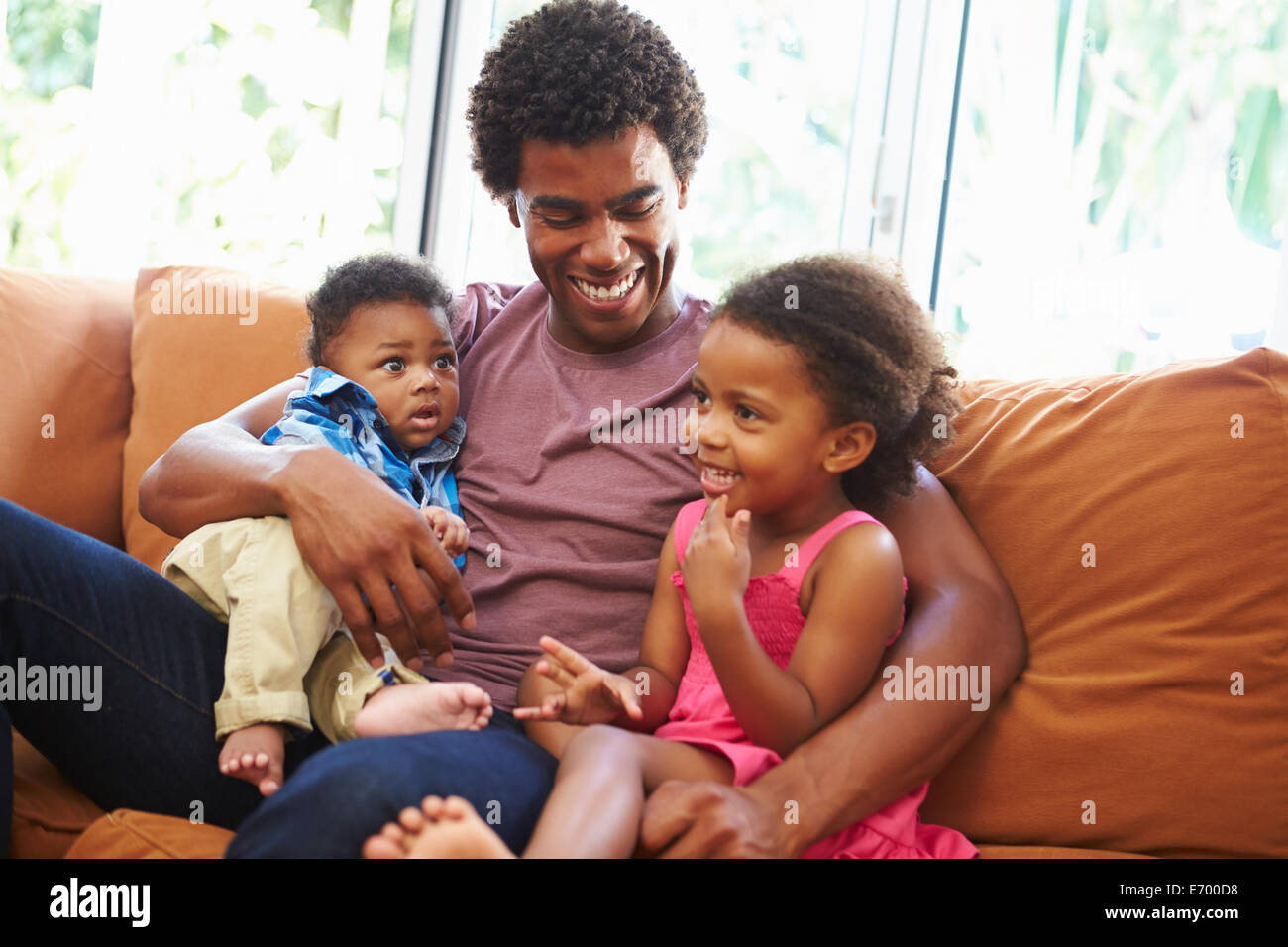 Father Relaxing On Sofa With Young Children Stock Photo