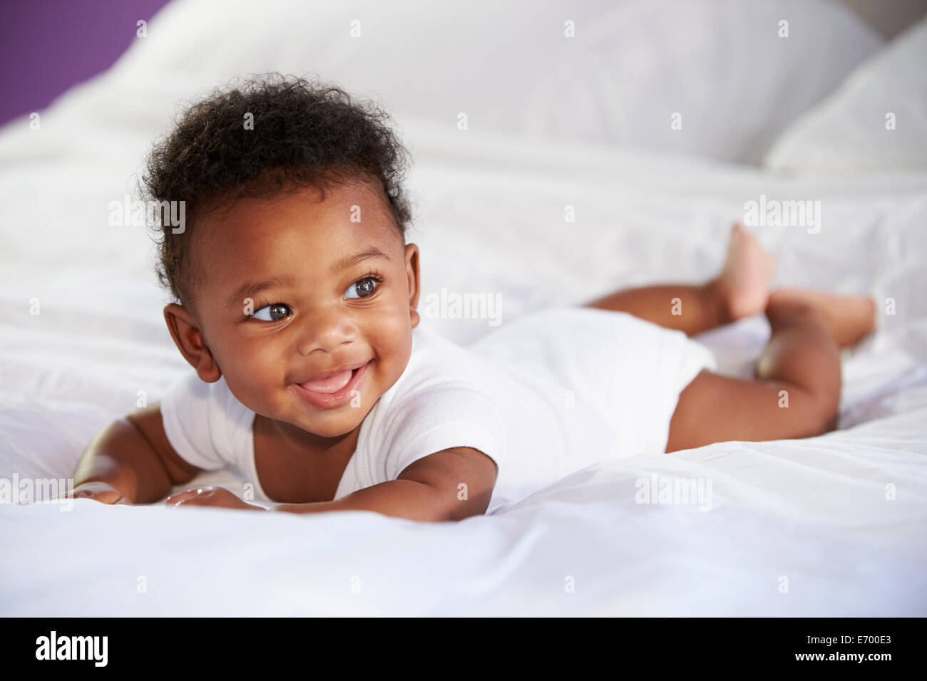 Cute Baby Lying On Tummy In Parent's Bed Stock Photo