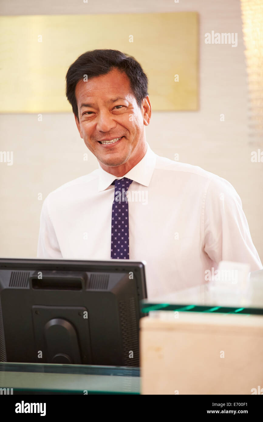 Portrait Of Male Receptionist At Hotel Front Desk Stock Photo