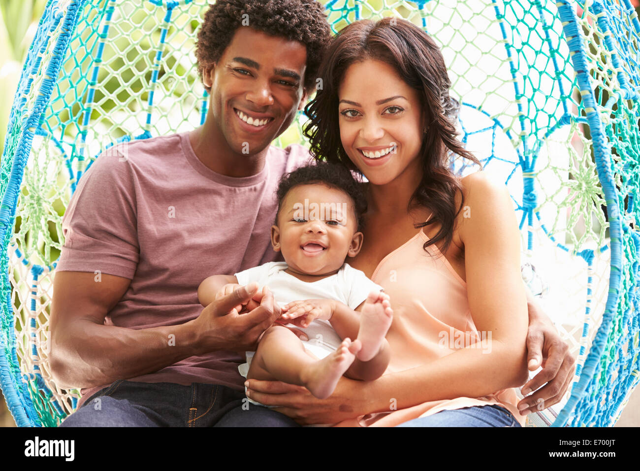Family With Baby Relaxing On Outdoor Garden Swing Seat Stock Photo