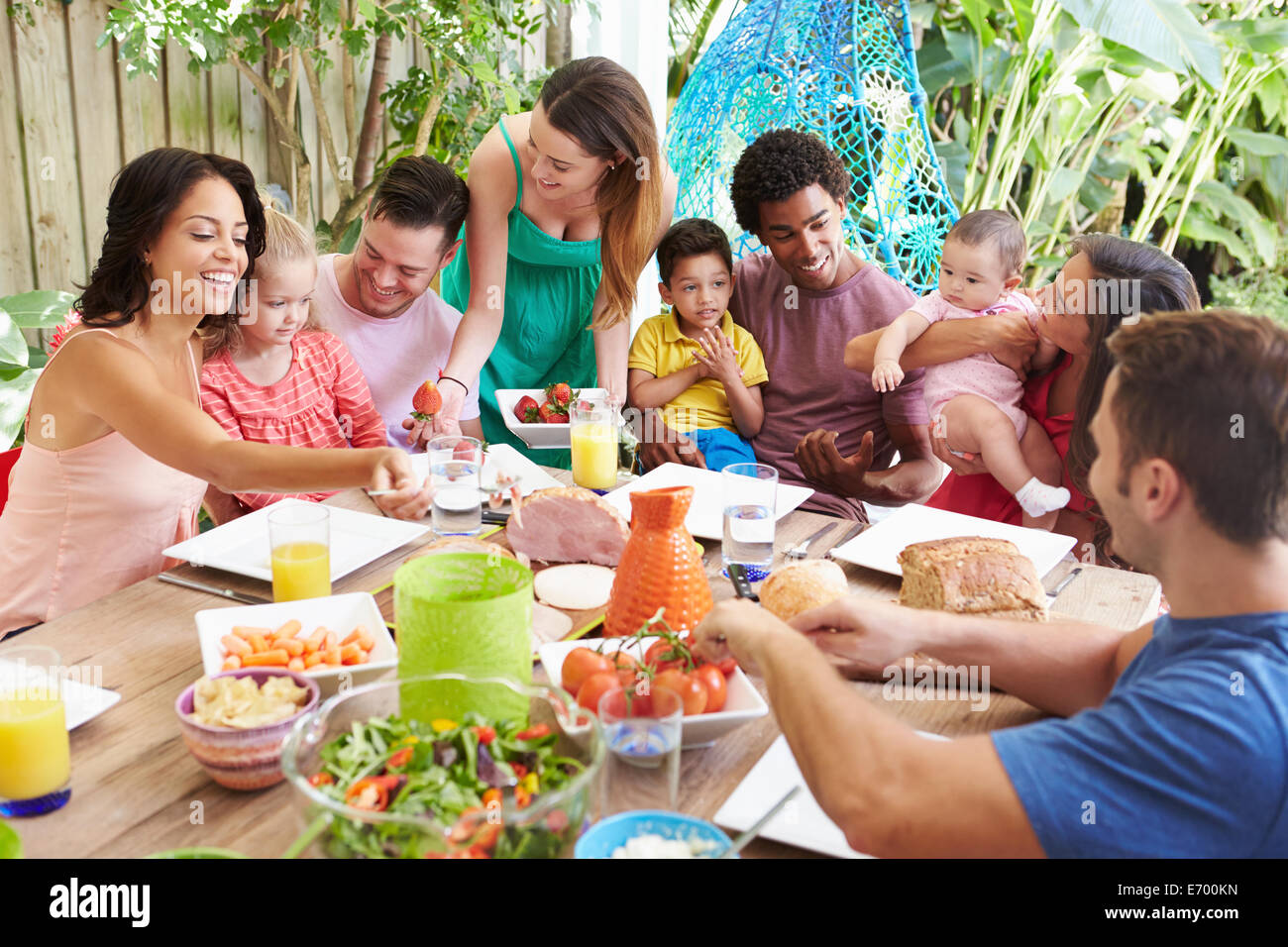 Group Of Families Enjoying Outdoor Meal At Home Stock Photo