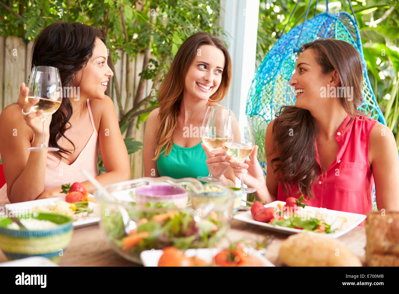 Three Female Friends Enjoying Meal Outdoors At Home Stock Photo