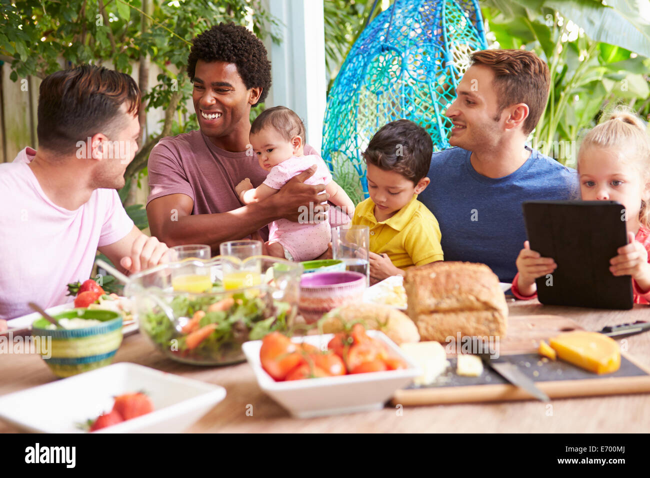 Group Of Fathers With Children Enjoying Outdoor Meal At Home Stock Photo