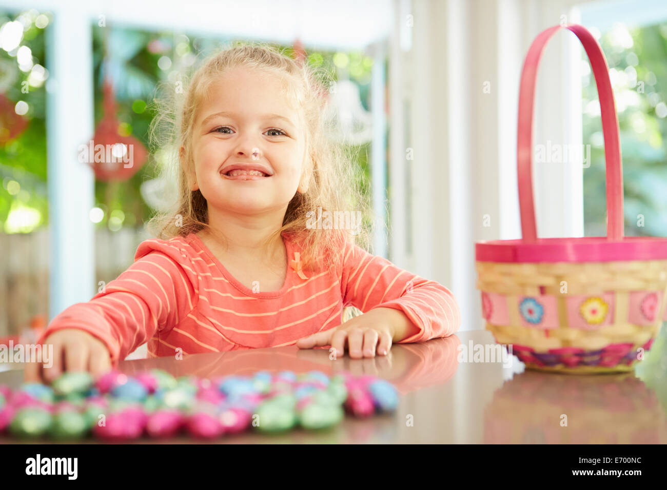 Girl With Chocolate Easter Eggs And Basket At Home Stock Photo