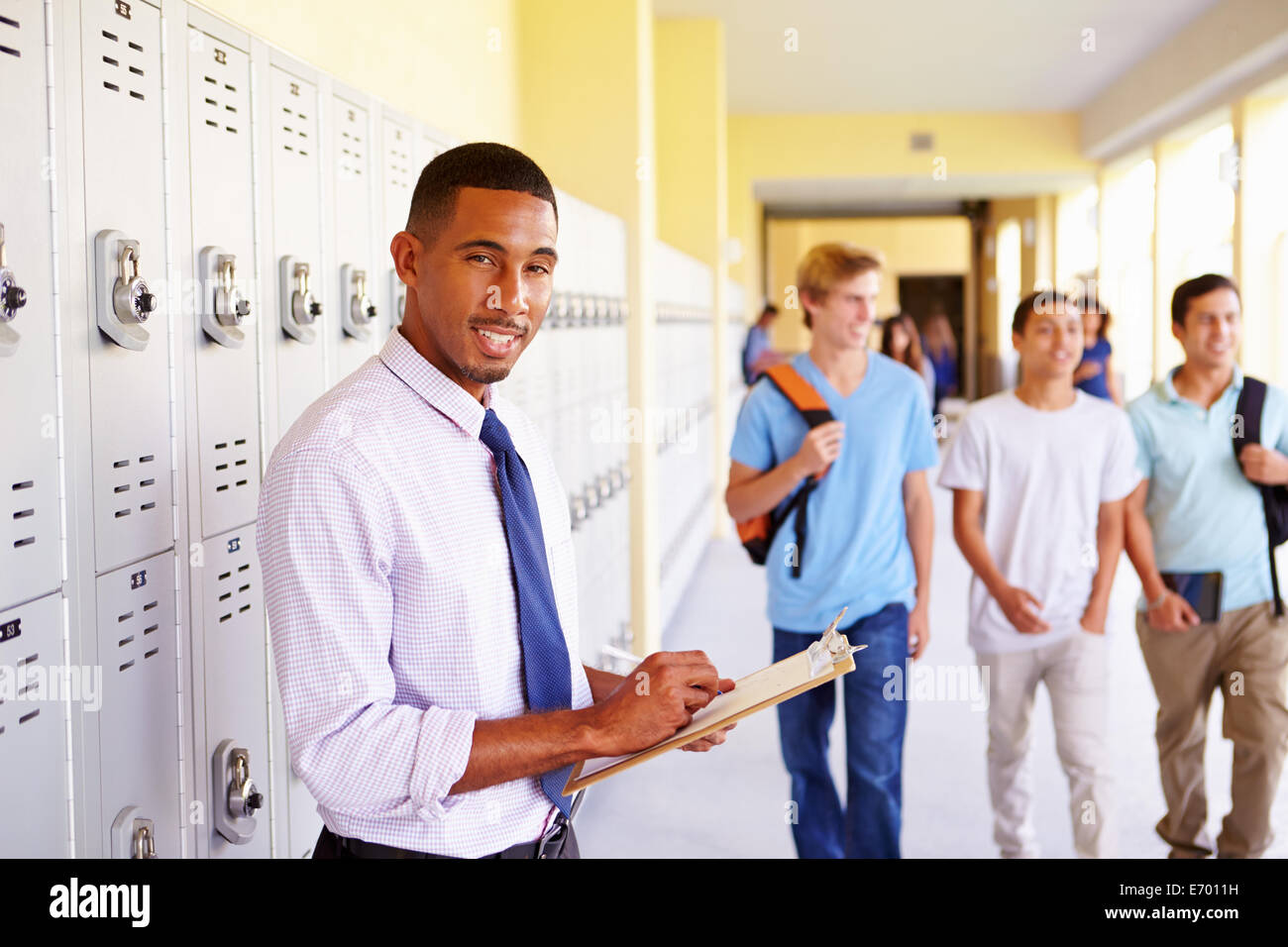 Male High School Teacher Standing By Lockers Stock Photo