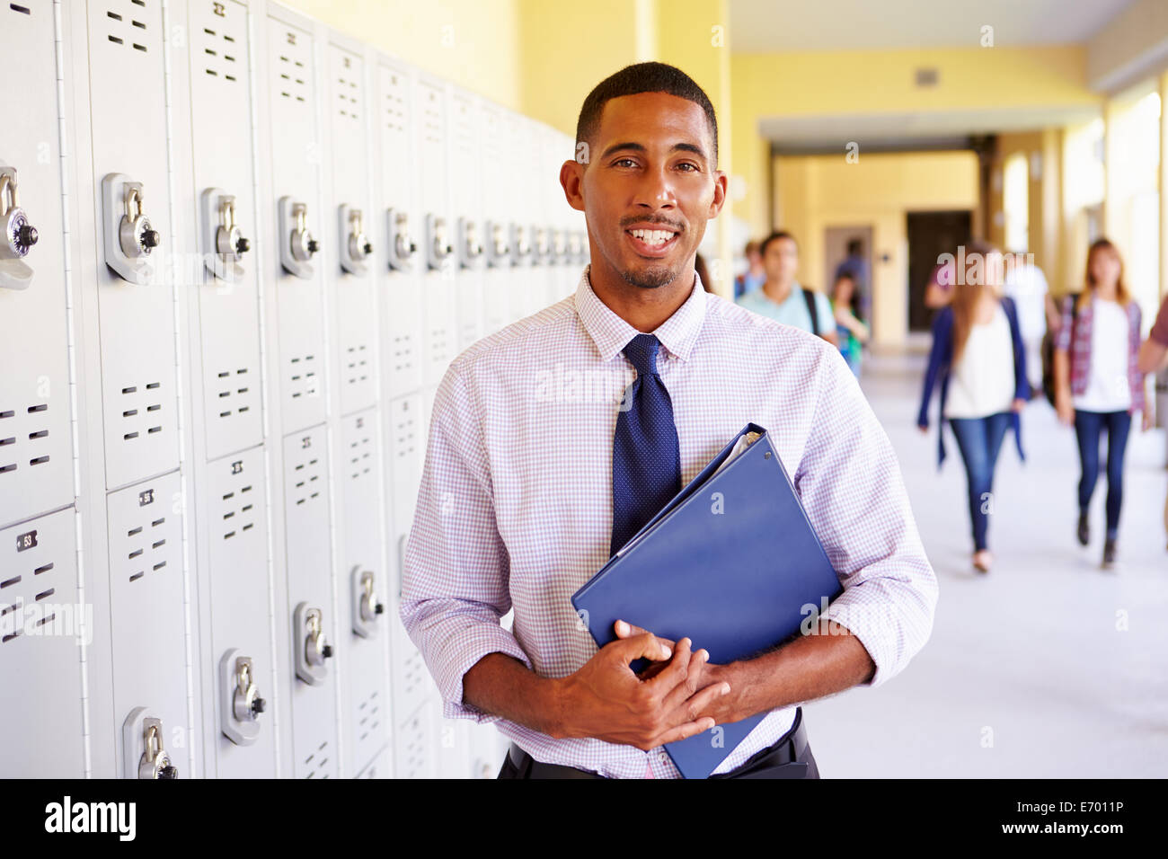 Male High School Teacher Standing By Lockers Stock Photo