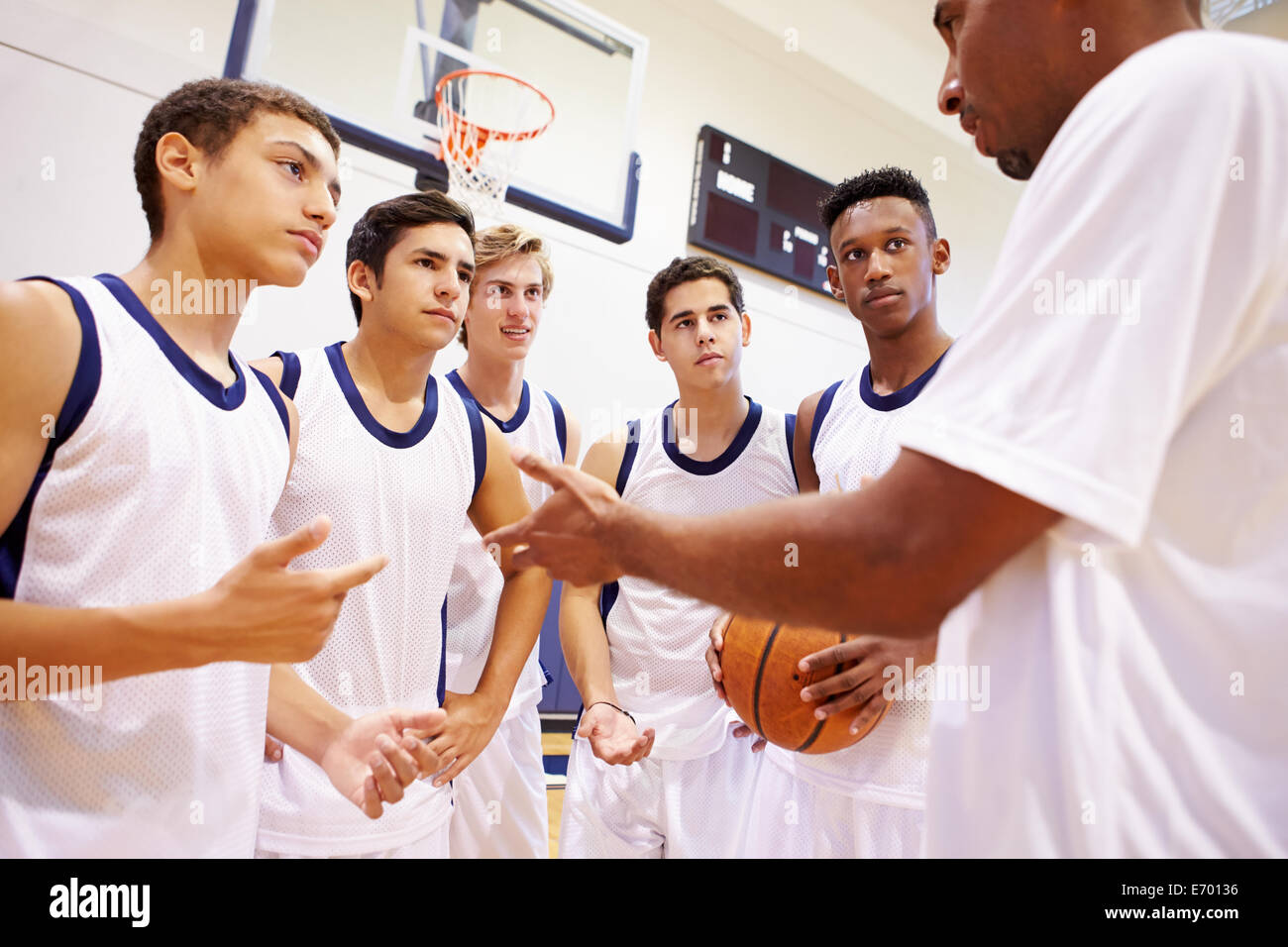 Male High School Basketball Team Having Team Talk With Coach Stock