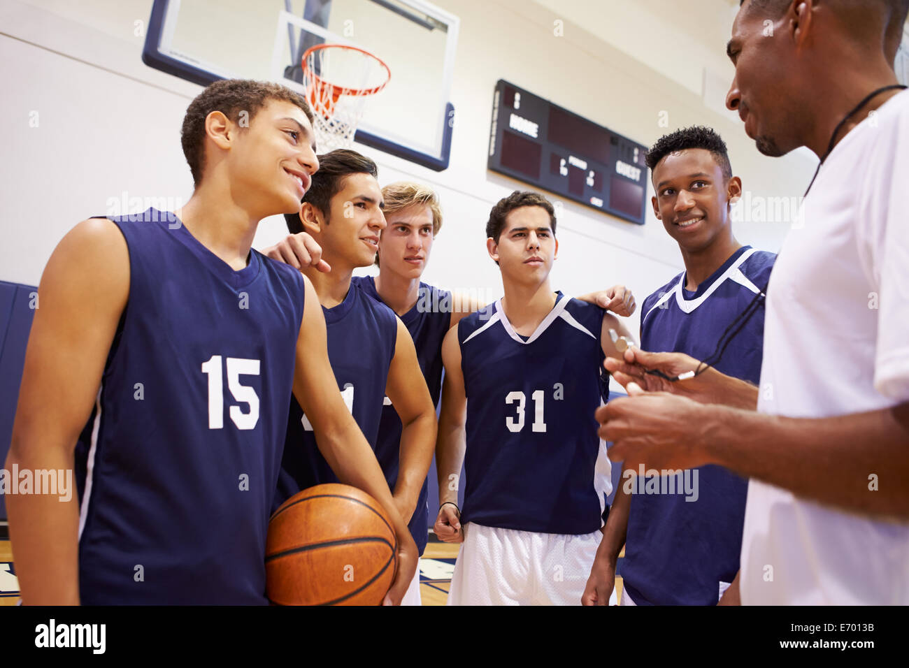 Male High School Basketball Team Having Team Talk With Coach Stock Photo