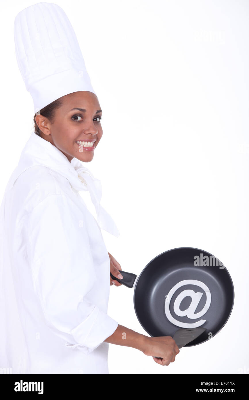 chef holding frying pan with at symbol Stock Photo