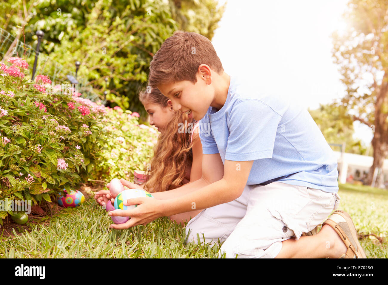 Two Children Having Easter Egg Hunt In Garden Stock Photo