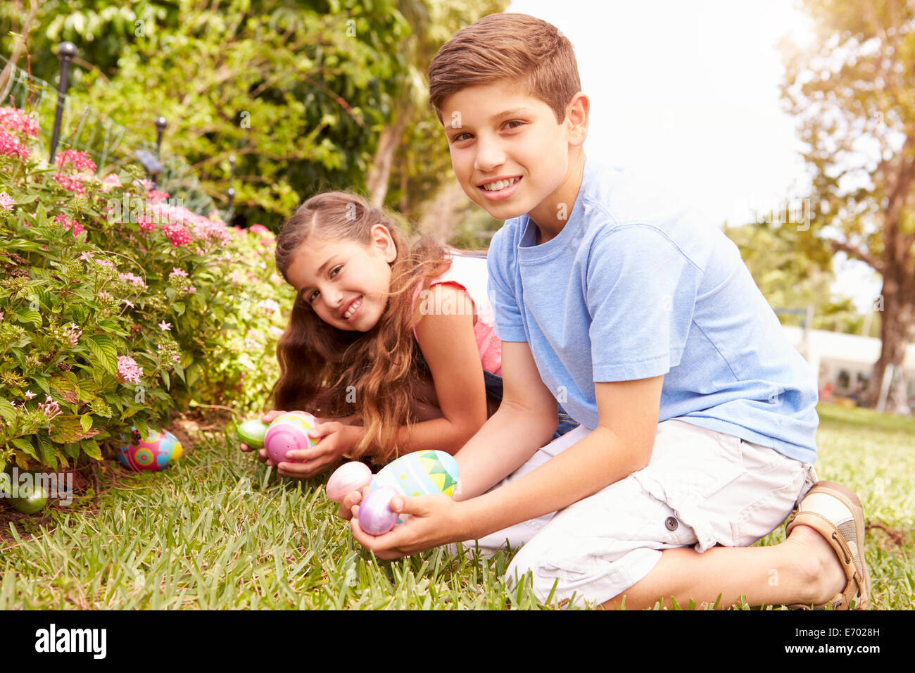 Two Children Having Easter Egg Hunt In Garden Stock Photo