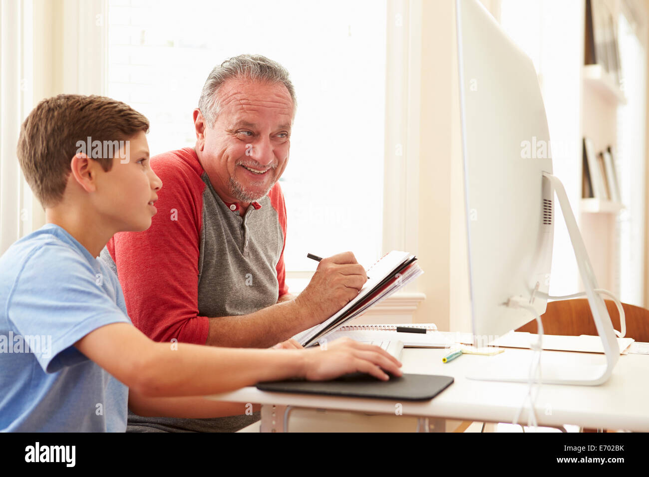 Grandson Teaching Grandfather To Use Computer Stock Photo