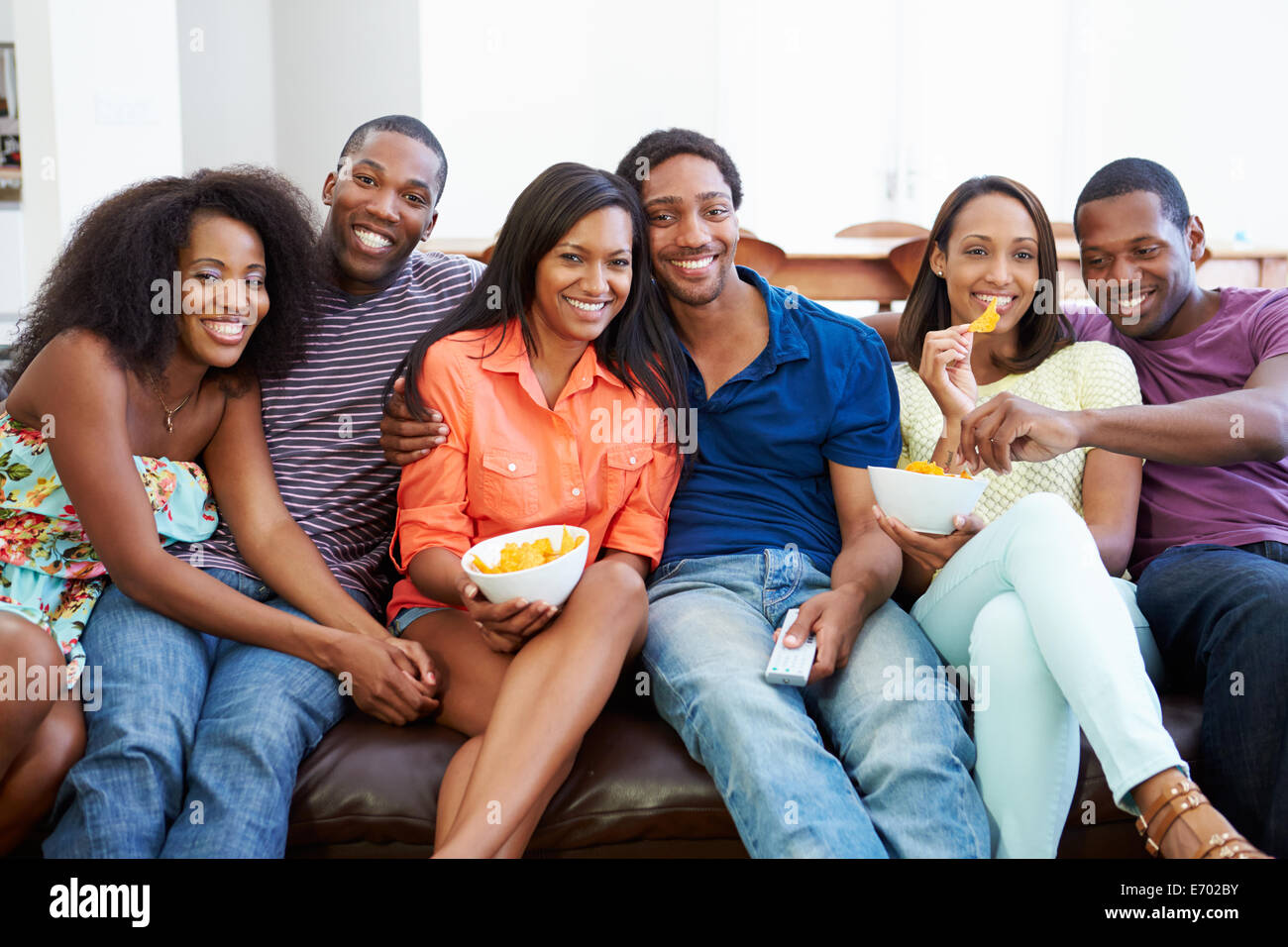 Group Of Friends Sitting On Sofa Watching TV Together Stock Photo