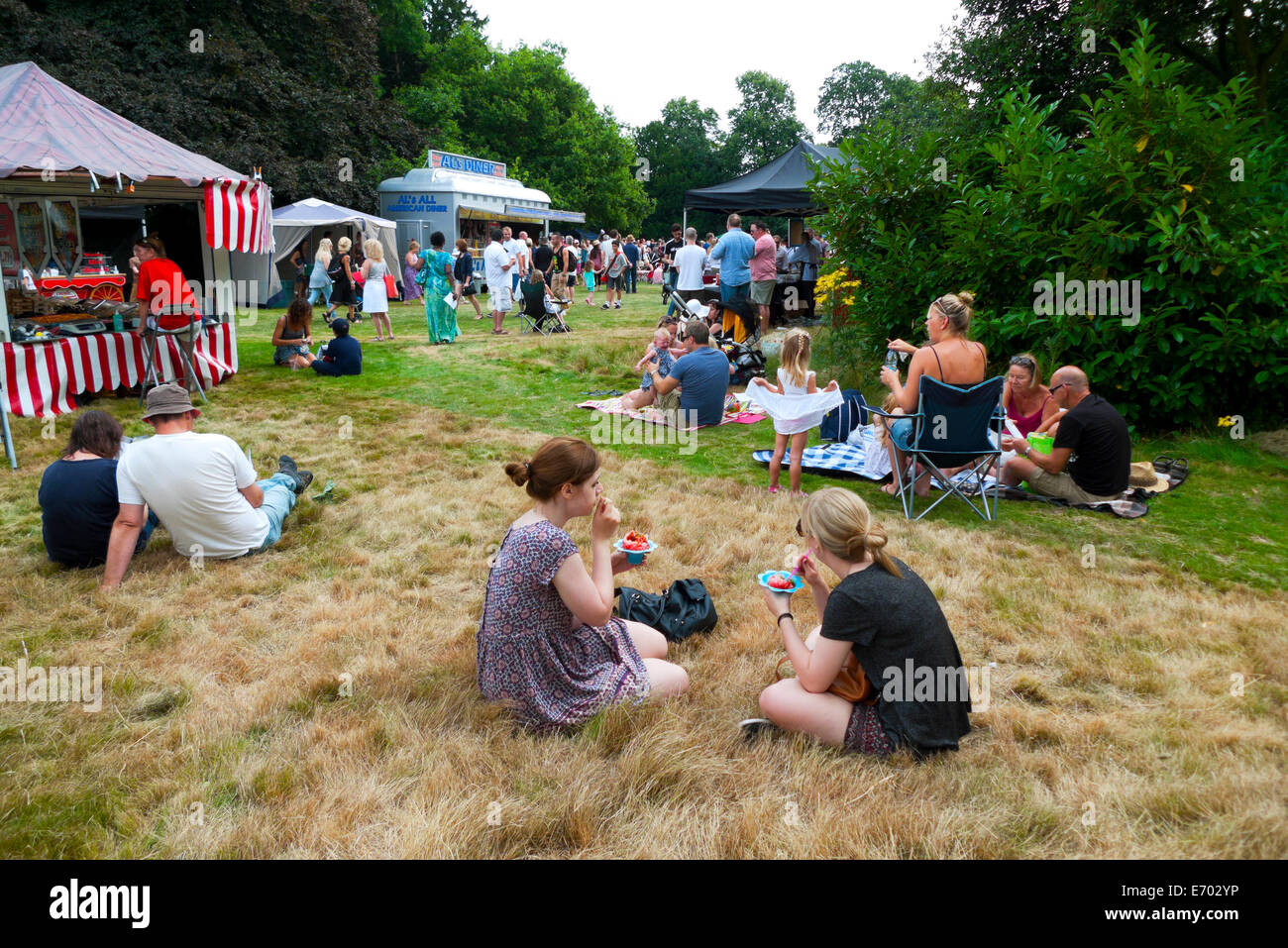 People sitting in the gardens at Strawberry Hill House eating strawberries at summer fair in Twickenham, London  KATHY DEWITT Stock Photo