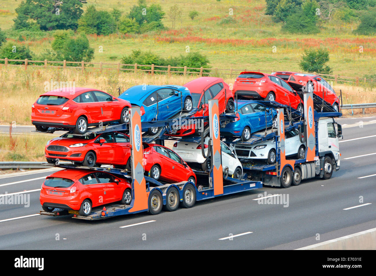 Ford motor company lorry truck car delivery transporter with trailer loaded with eleven new red white & blue cars driving on motorway Essex England UK Stock Photo