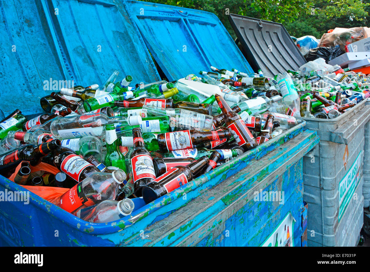 Rubbish bins overflowing with glass bottles in roadside recycling