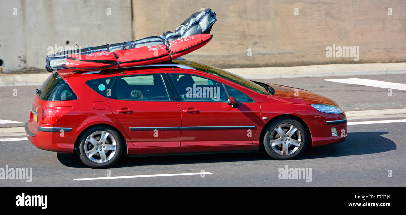 Car driving along motorway with roof rack loaded with luggage bags bending from wind pressure       cars Stock Photo