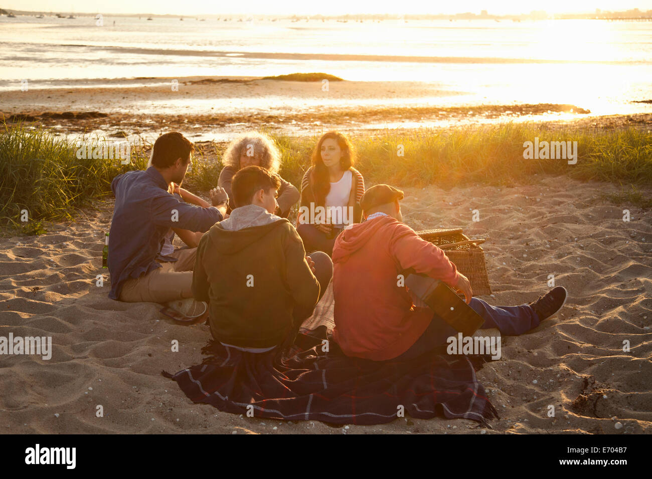 Five adult friends picnicing at sunset on Bournemouth beach, Dorset, UK Stock Photo