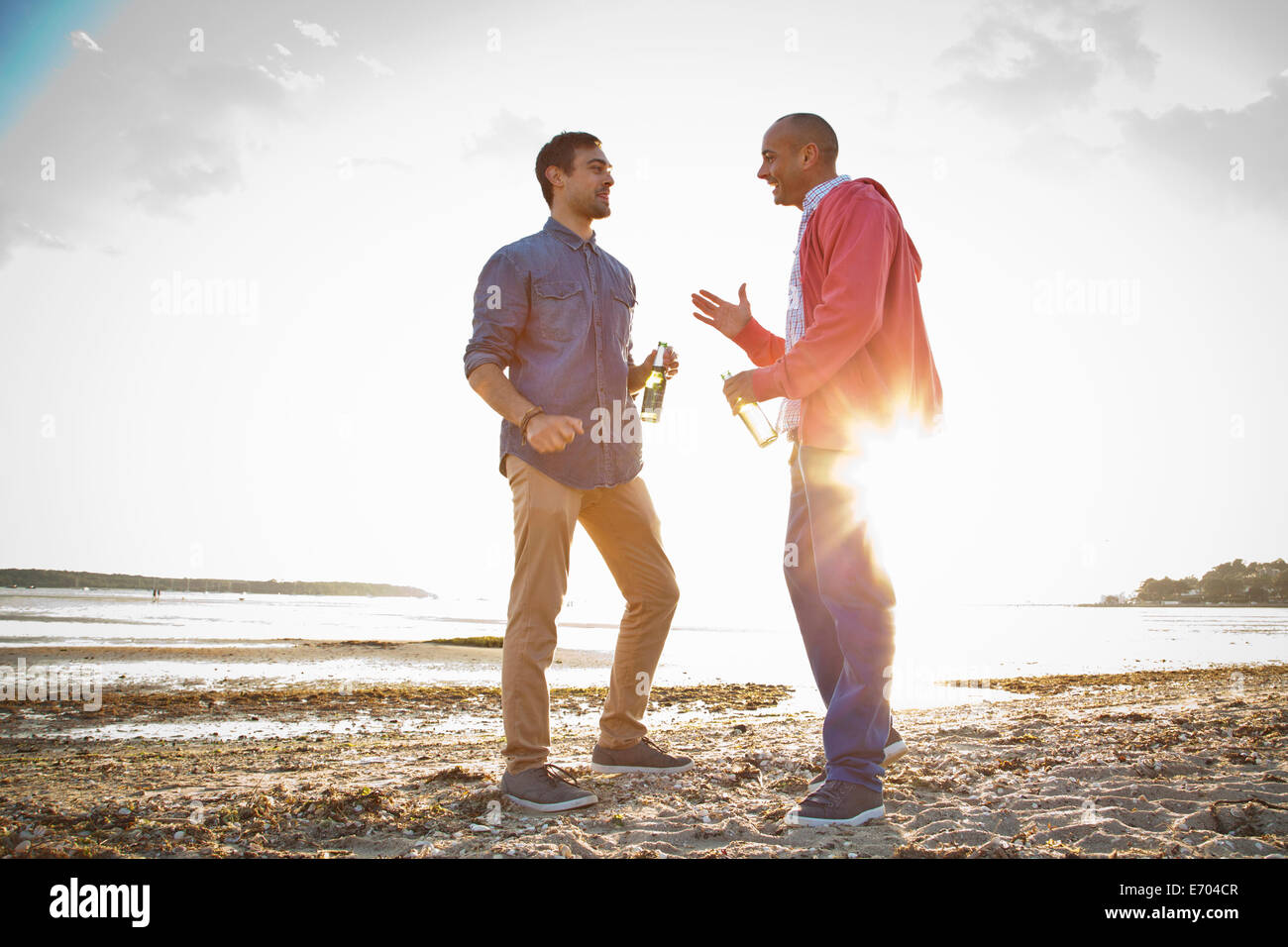 Men drinking beer and chatting on beach Stock Photo