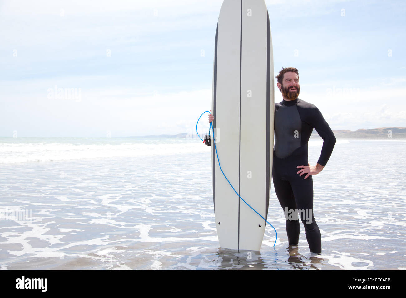 Portrait of young male surfer standing in sea with surfboard Stock Photo