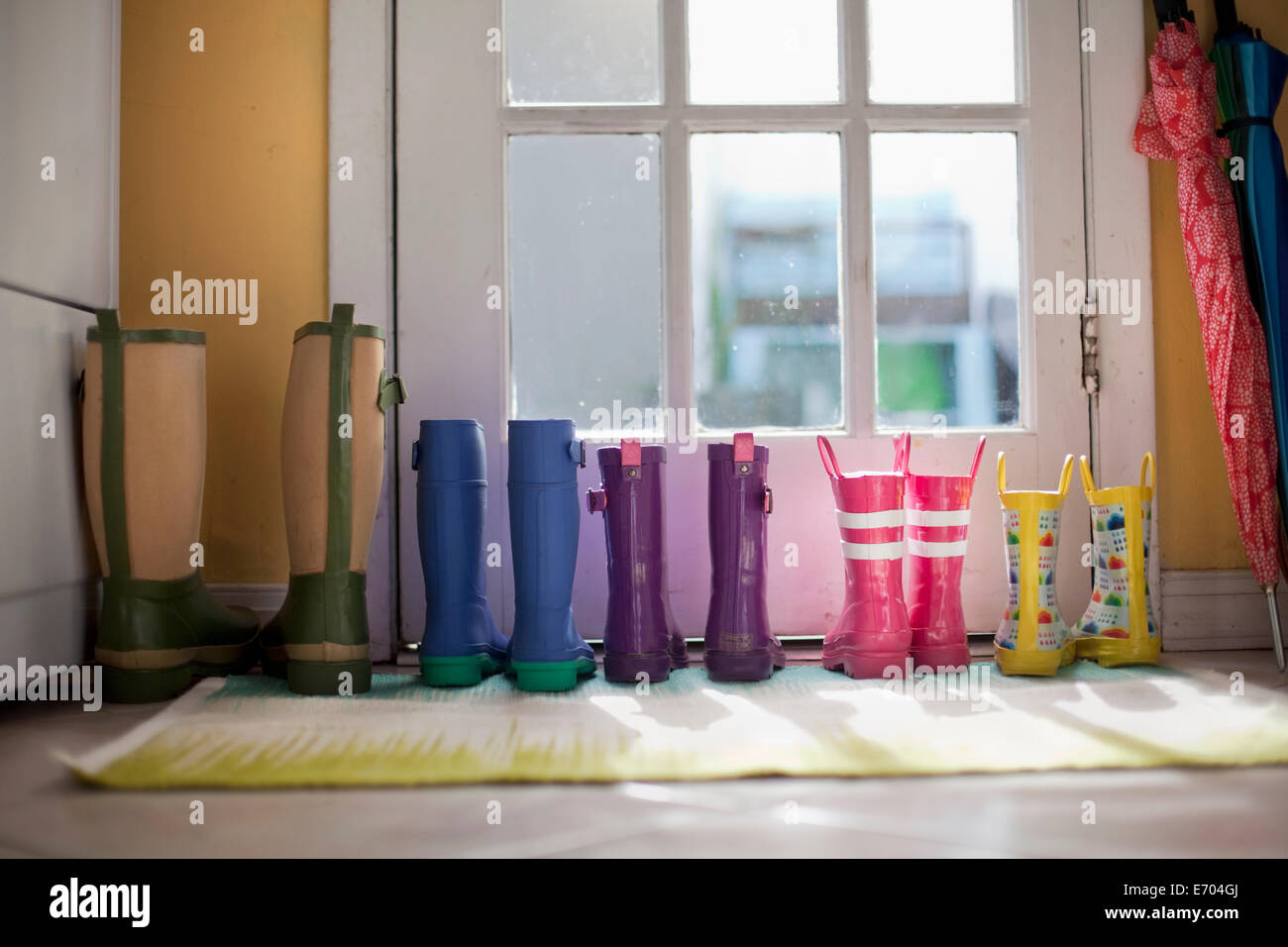 Tidy row of rubber boots at back door Stock Photo