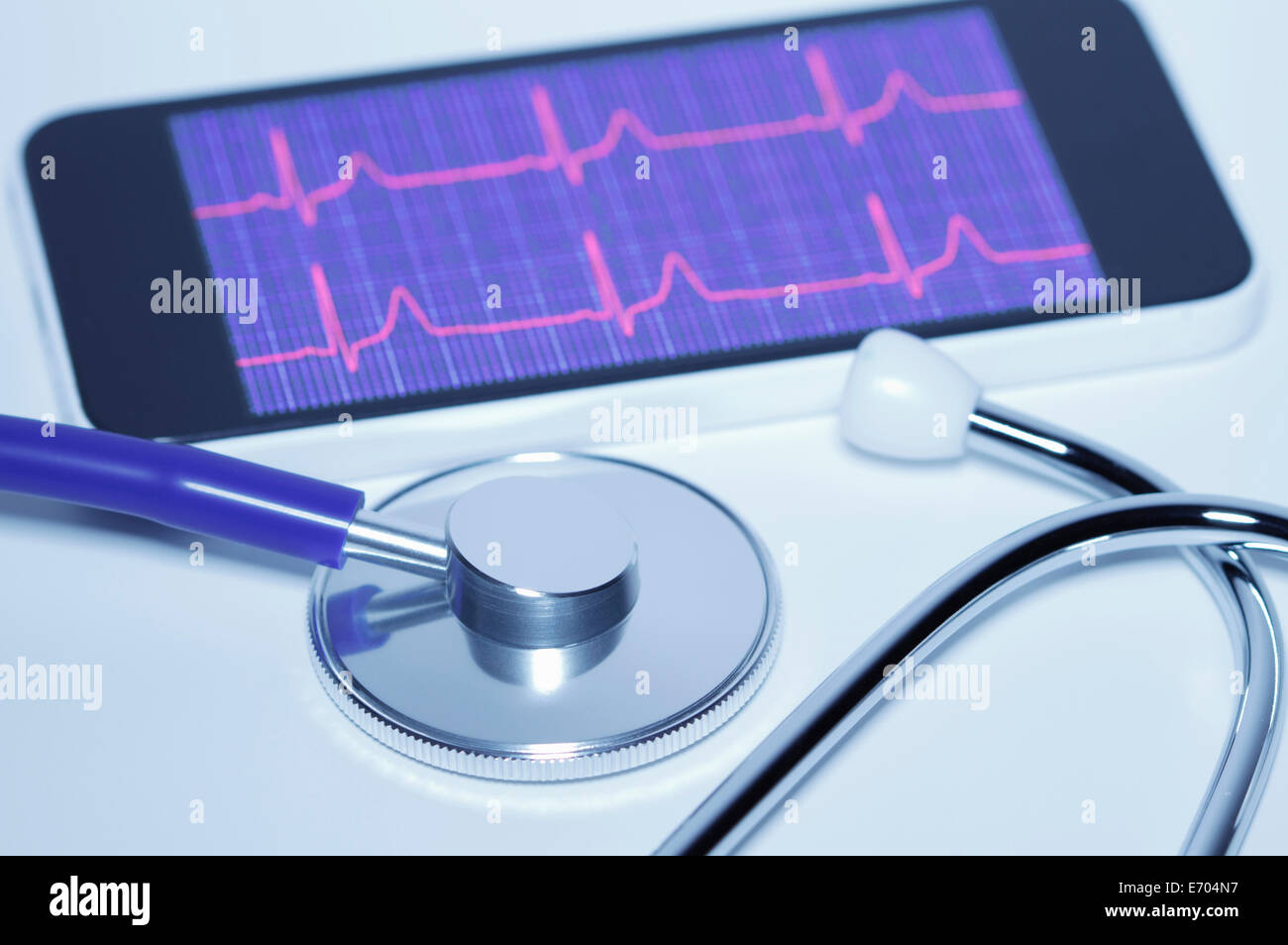 An acoustic stethoscope and smartphone screen displaying an electrocardiogram Stock Photo