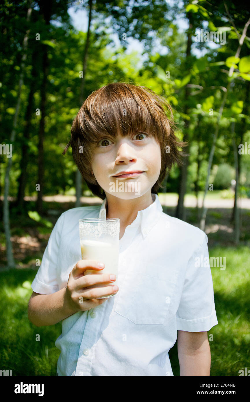 Boy in woods drinking milkshake and pulling a face Stock Photo
