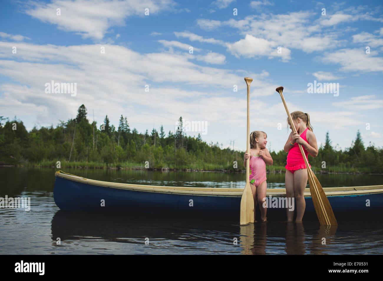 Two young sisters chatting next to canoe on Indian river, Ontario