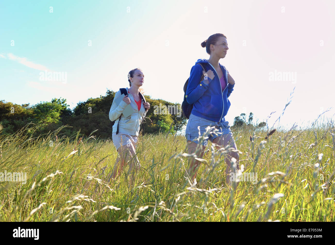 Two young women hiking through field Stock Photo