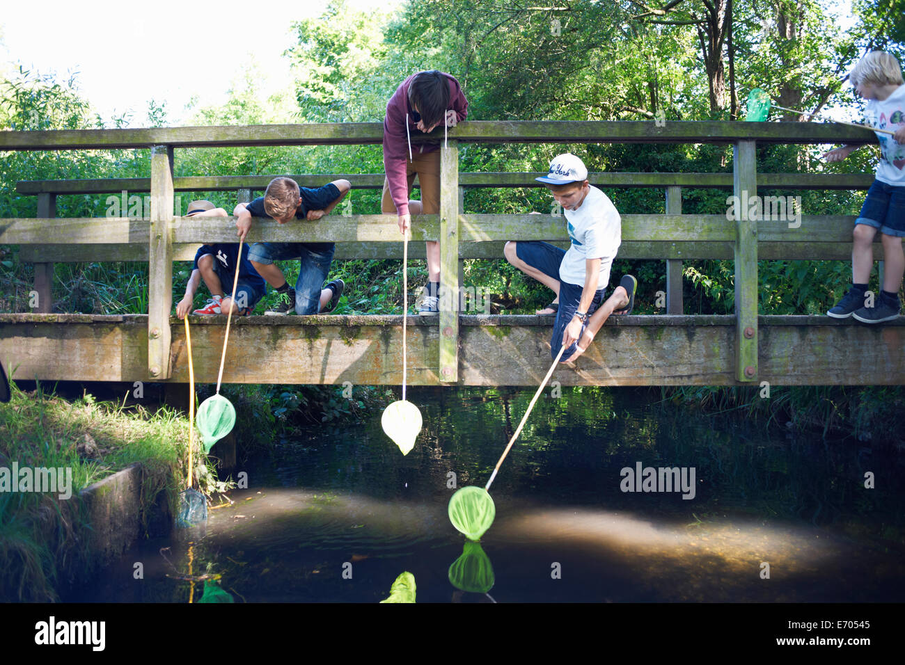 Boys using fishing nets on bridge Stock Photo