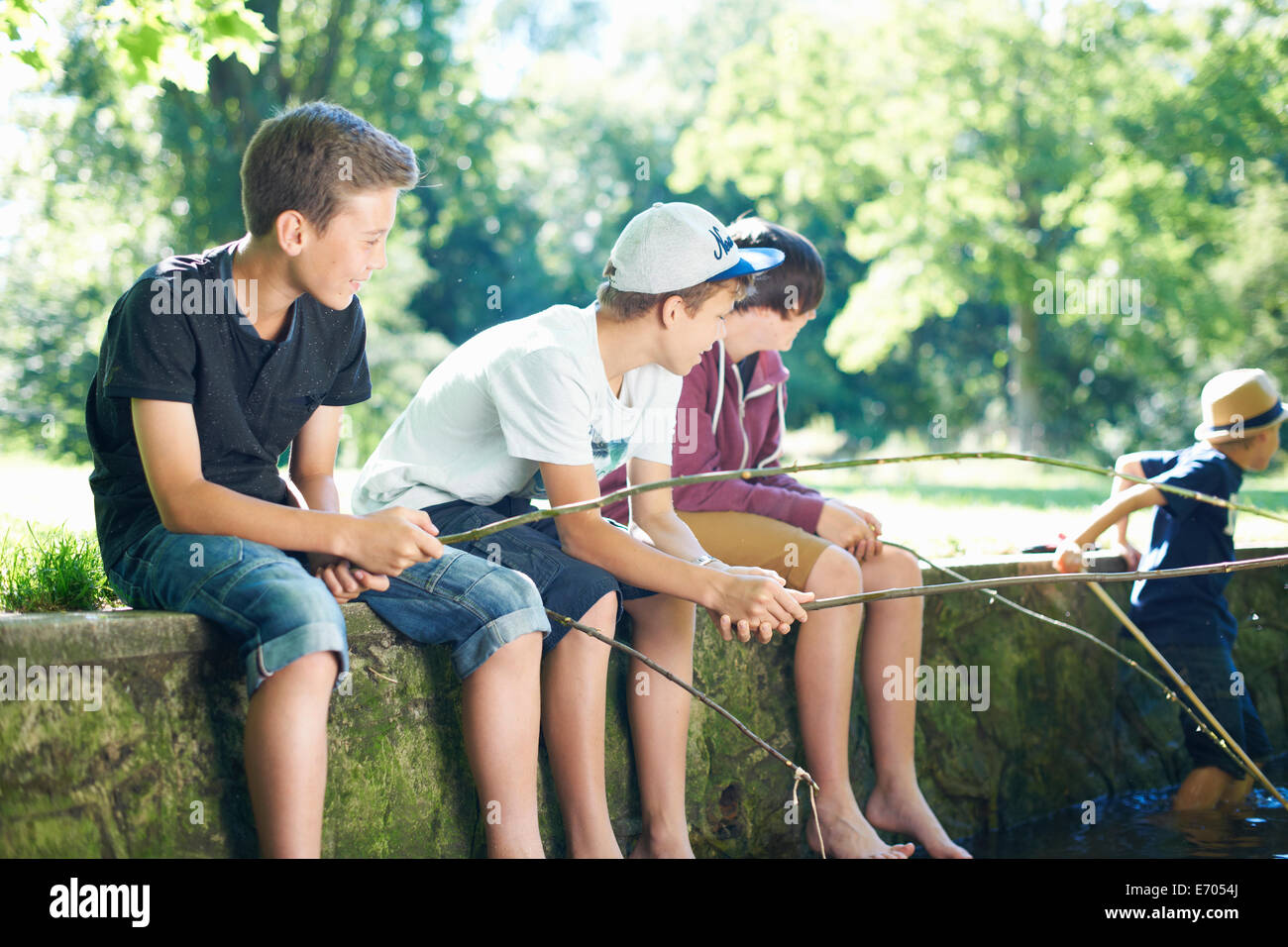 Boys sitting on wall, fishing Stock Photo