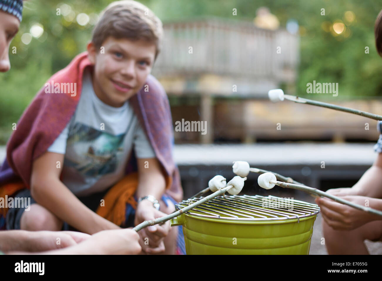Group of young boys toasting marshmallows over bucket barbecue Stock Photo