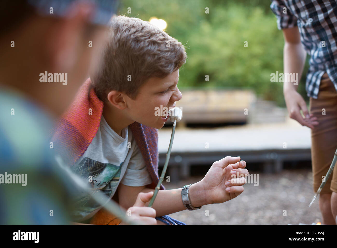 Young boy eating toasted marshmallow from stick Stock Photo