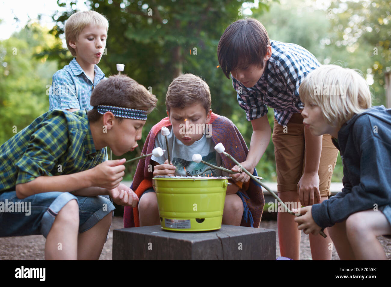 Group of young boys toasting marshmallows over bucket barbecue Stock Photo