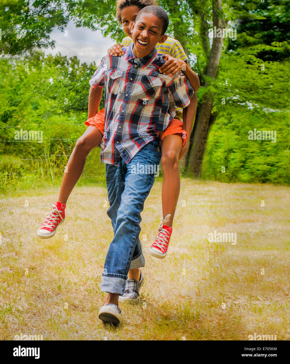 Teenage boy giving friend piggyback ride Stock Photo