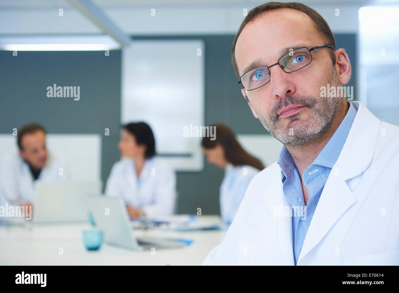 Portrait of male doctor, colleagues having discussion behind Stock Photo