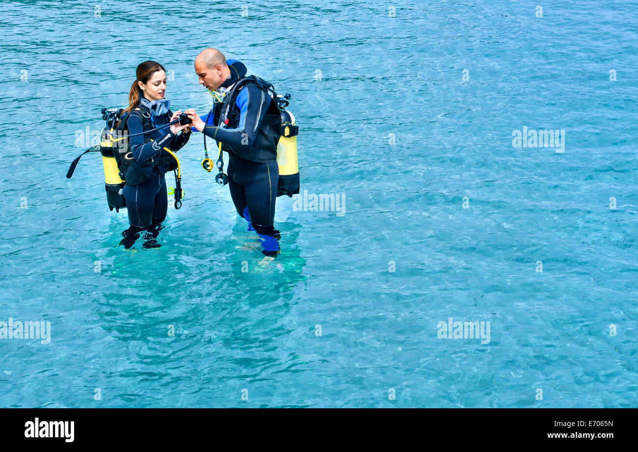 Couple preparing to scuba dive in sea, La Maddalena, Sardinia, Italy Stock Photo