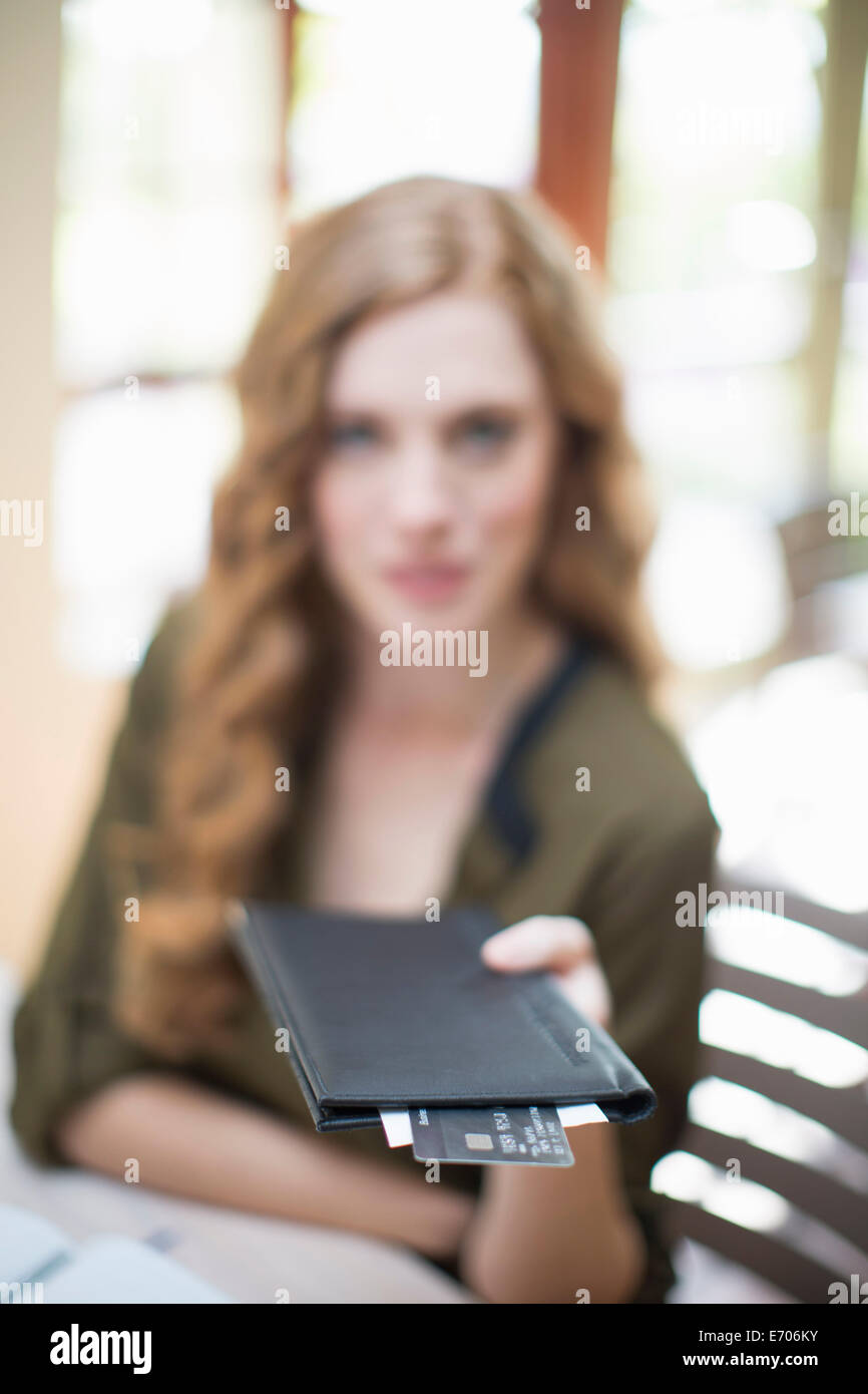 Young woman holding up bill and credit card in restaurant Stock Photo