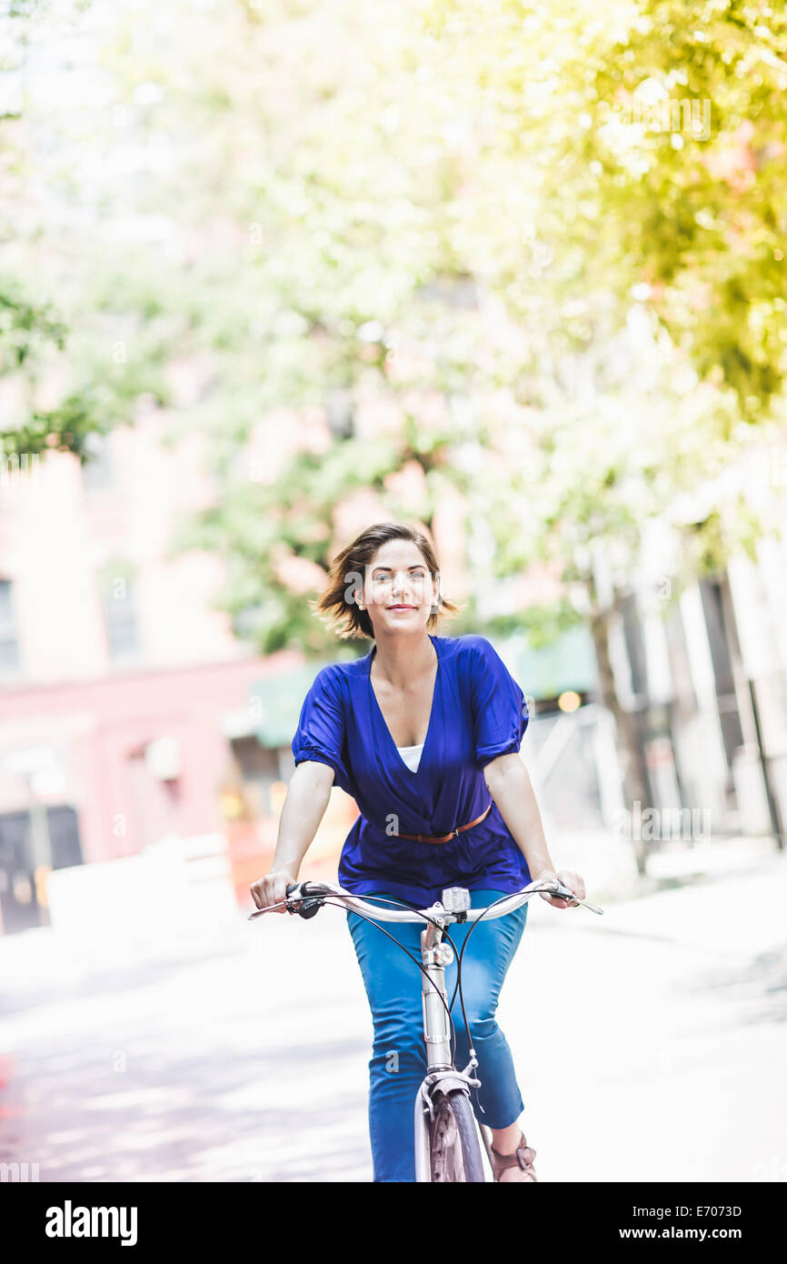 Mid adult woman cycling on city street, New York City, USA Stock Photo